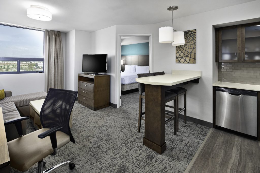 one bedroom hotel suite with chair, desk, kitchenette in irvine ca