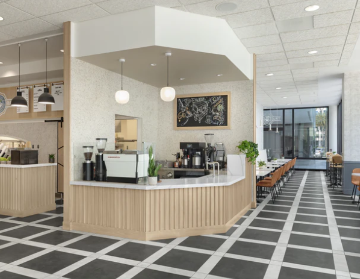 interior of tru bru coffee shop with ceiling lights, white tables on the side, chairs, and a serving counter